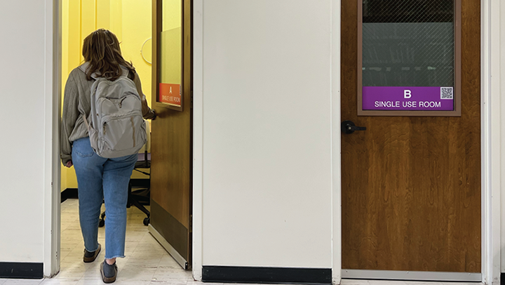 A student with a backpack walking into a single-use room labeled “A” in a hallway with another door labeled “B Single Use Room.”
